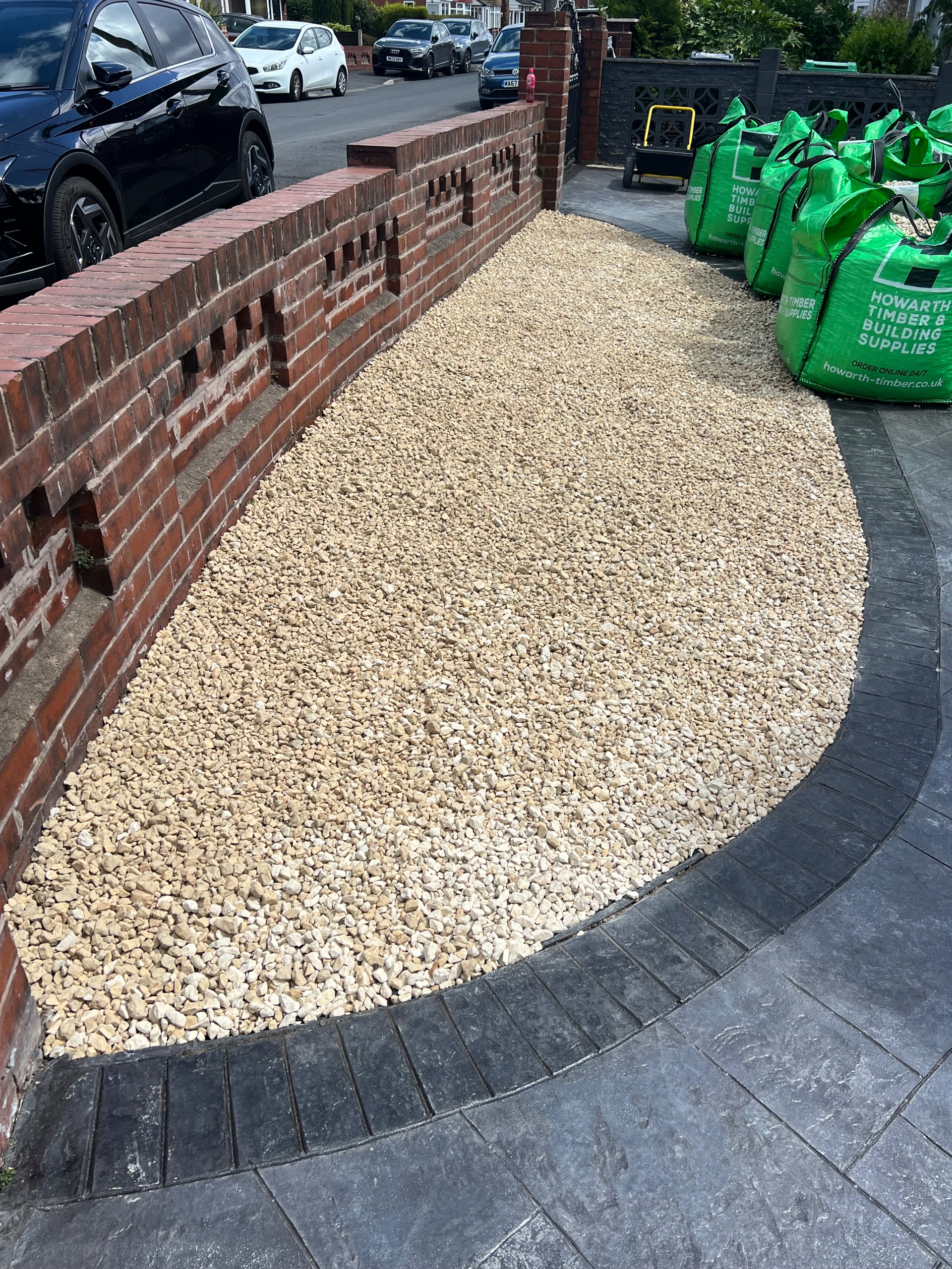 gravel bed edged by charcoal block paving on residential front garden with Howarth Timber supply bags